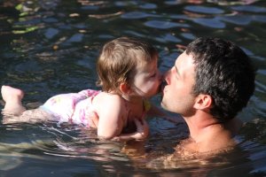 Jolee Kate floating and kissing on her daddy.